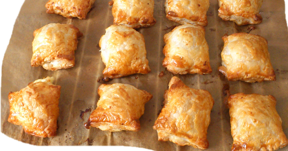 Golden baked pirozhki stuffed buns arranged on a wooden board, showing their soft glazed tops and stuffed savory filling